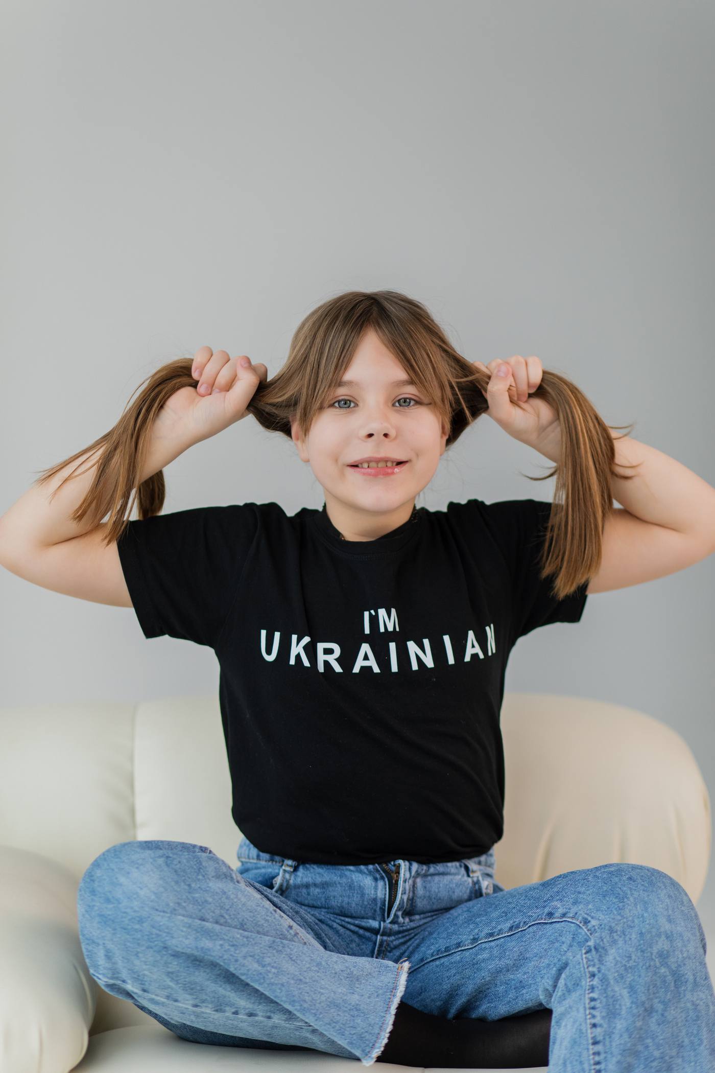 Дівчинка тримає себе за хвостики й сміється
